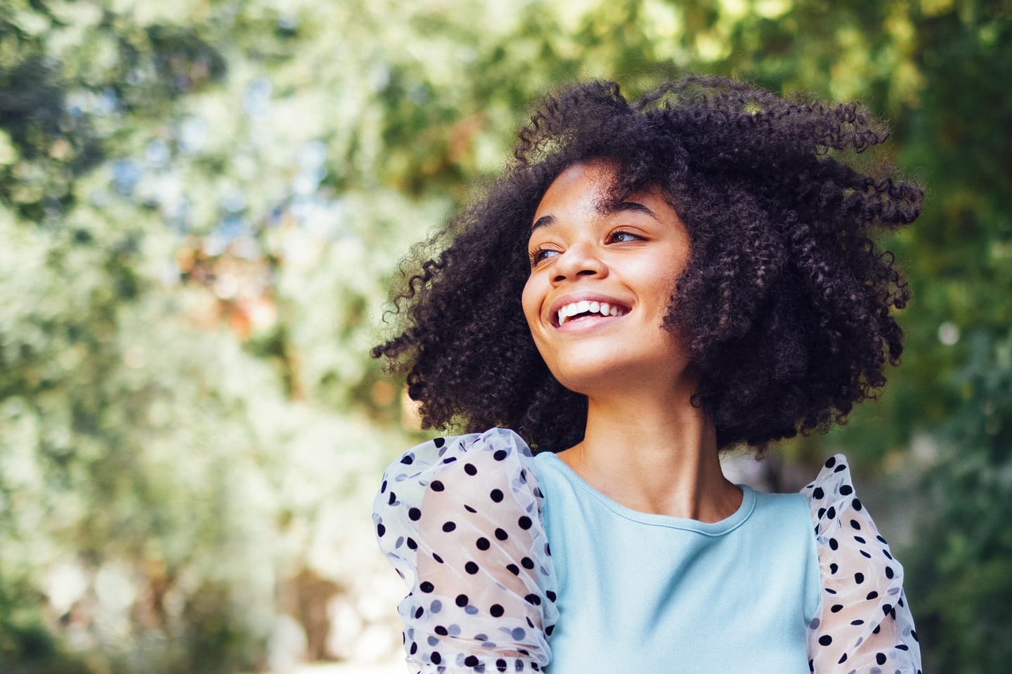 A smiling teenager outdoors in natural light.